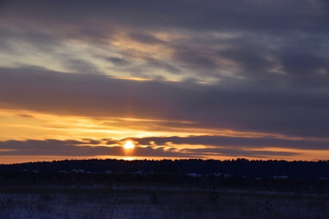 Winter sunset in the village over the forest