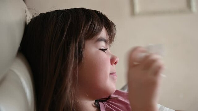 a 10-year-old girl lies in bed sick, coughs, blows her nose into a napkin. High quality 4k footage