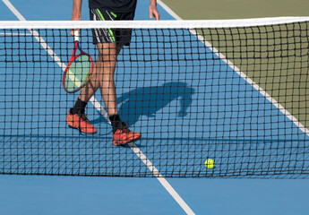 Tennis player with racket and ball on blue hard tennis court near net. Sports, active game...