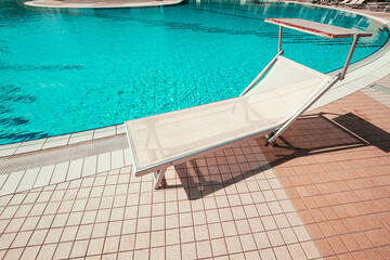 Obraz na płótnie Canvas Resort pool. Summer resort chair, relax lounge at luxury hotel pool. Beach lounger chaise. Vacation sunbed. Blue water, sunny happy travel holiday.