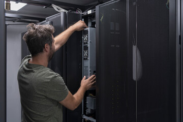Fototapeta na wymiar IT engineer working In the server room or data center The technician puts in a rack a new server of corporate business mainframe supercomputer or cryptocurrency mining farm. 