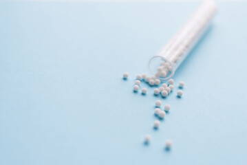 Homeopathic pills and plastic container on a blue background. Homeopathic medicine	