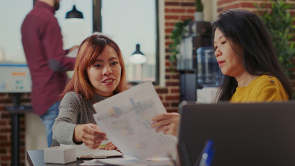 Coworkers doing teamwork to analyze graphics on files in company office. Business people working in collaboration to plan strategy and investment for management career. Partners meeting