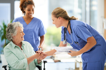 Shot of an attractive female nurse holding medical records while shaking hands with her...