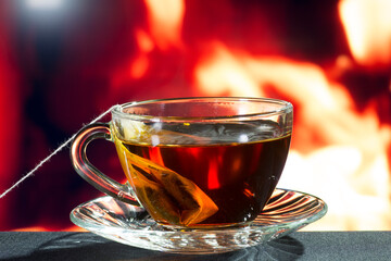 glass cup of black tea on a background of fire