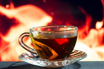 glass cup of black tea on a background of fire