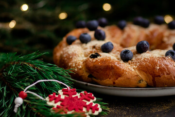 Homemade pie with berries close-up on a dark background with fir branches. In the foreground is a red wooden snowflake