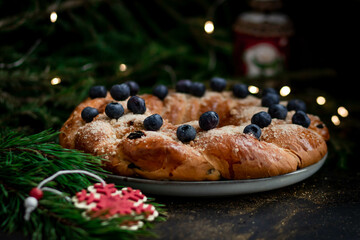 Homemade pie with berries close-up on a dark background with fir branches. In the foreground is a red wooden snowflake