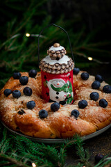 Homemade pie with berries close-up on a dark background with fir branches. In the center of the pie is a ceramic Christmas lantern