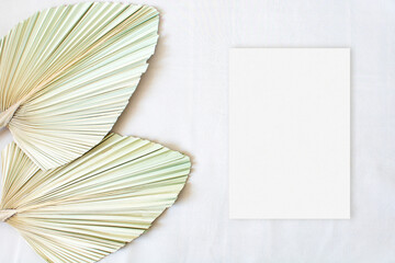 Top view mockup wedding card with leaf palm on the beige background
