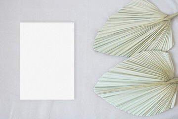 Top view mockup wedding card with leaf palm on the beige background