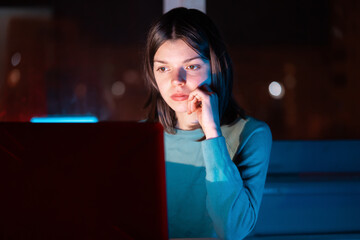 Girl is working on a laptop at night at home.