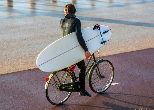 a man on a bicycle with surfboard