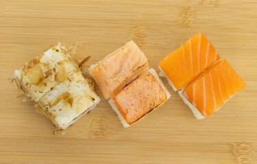 Set of sushi maki rolls with fresh salmon, fried salmon and in dry tuna shavings on wooden board. Top view