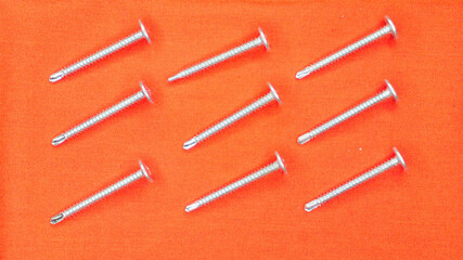 
Self-tapping screws, photo on a red background