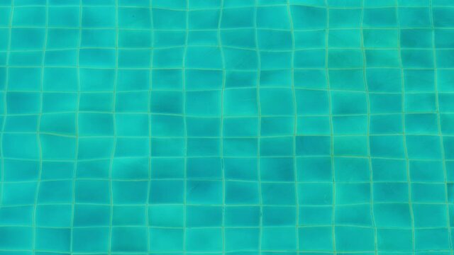 Clean water at empty pool, bottom tiles seen through waving surface. Green-blue colour from water or floor, image wobble due to refraction in small waves