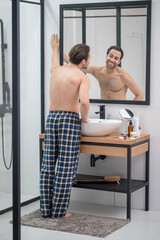 Man in plaid home pants standing at the mirror