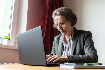 senior old woman female sit desk, home office online notebook laptop work business distance freelancer