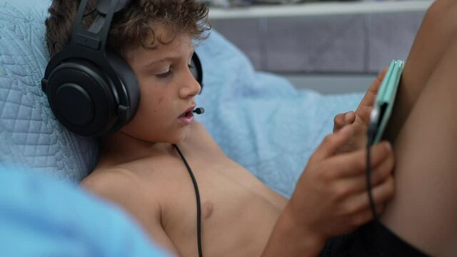 A preteen boy playing with tablet online wearing headset