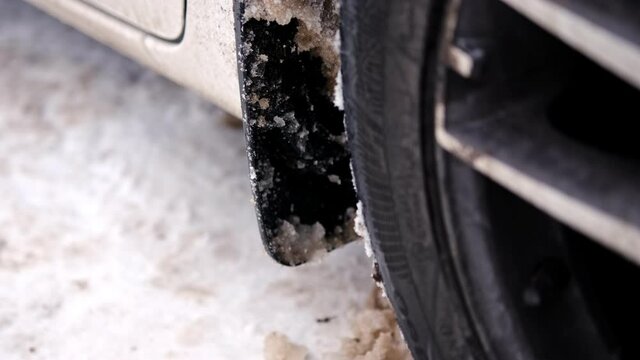 Woman in Classy Leather Shoes Kicking Car Wheel Mud Flap Mudguard to Remove Clumps of Frozen Snow Slush on Cold Winter Day
