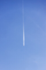 Condensation light line in the sky from aircraft. Trail of the plane on blue background. Airplane...