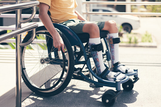 Young man with disability with using wheelchair by himself on public ramps in hospitals or schools background, Pictures of the facilities or equipment and transportation for people with disabilities.