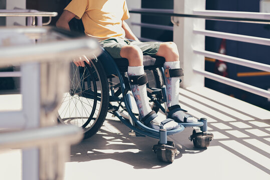 Young man with disability with using wheelchair by himself on public ramps in hospitals or schools background, Pictures of the facilities or equipment and transportation for people with disabilities.