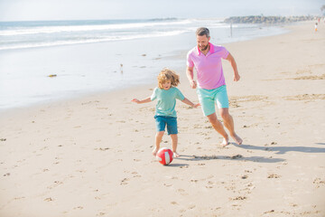 happy father and son play football on summer beach with ball, friendship