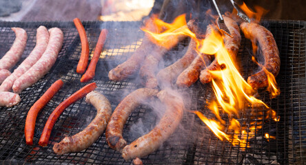 Butifarras (botifarra) a la brasa o parrilla (embutido fresco) con llamas (llamaradas) (humeando...