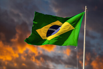 Bandeira brasileira tremulando ao vento. Bandeira do Brasil içada com céu e nuvens ao entardecer...