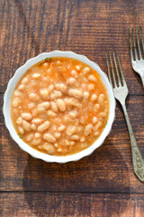  Homemade bean soup .Steamed white beans in tomato sauce  on a wooden background  