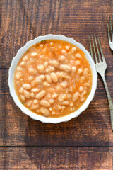  Homemade bean soup .Steamed white beans in tomato sauce  on a wooden background  