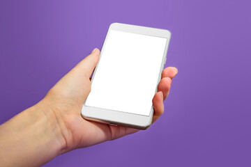 Mockup of a mobile phone with a white screen on a lilac background. Veri Peri Color of the Year 2022. female hand holding mobile phone isolated on purple background