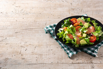 Salmon and avocado salad on rustic wooden table. Copy space