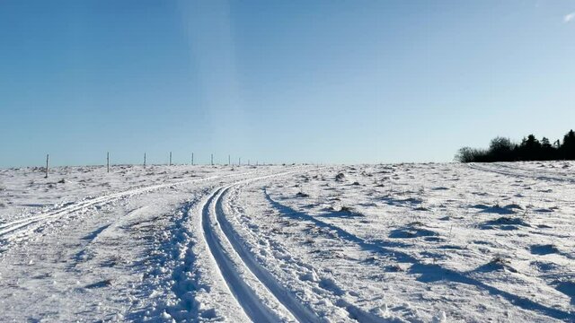 Sunny day and winter landscape with cross-country skiing trail in the snow on a meadow. Footage made in Sk&aring;ne, Sweden.