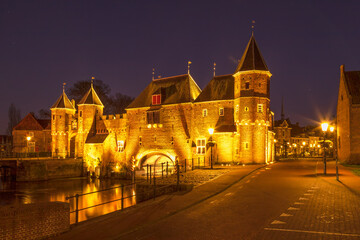 Fototapeta na wymiar Illuminated historic land and water gate de Koppelpoort at night in Amersfoort.