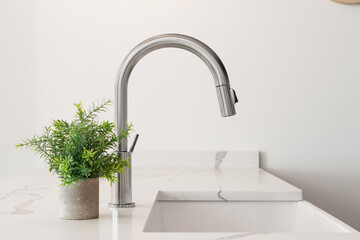 A kitchen sink detail shot with a farmhouse sink, stainless steel faucet, marble countertops, and a...