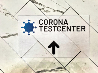Sign on the floor of a shopping mall pointing the way to a corona test center.