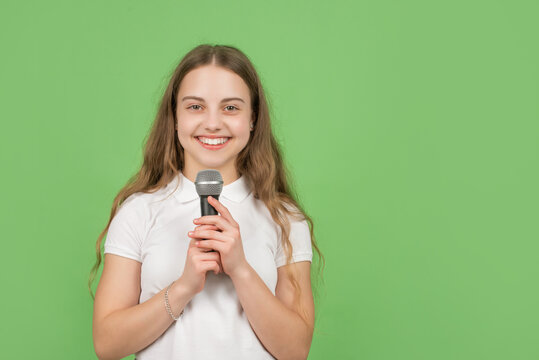 happy child singing in microphone on green background with copy space, music