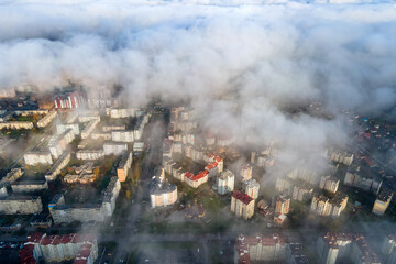 Top aerial view of fluffy white clouds over modern city with high rise buildings