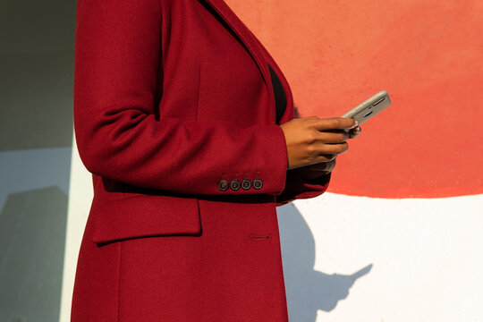 Anonymous African American woman in formal jacket with smartphone