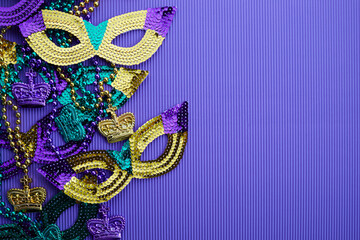 Frame of Mardi gras, venetian or carnivale mask and beads on a purple background