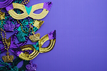 Frame of Mardi gras, venetian or carnivale mask and beads on a purple background © vetre