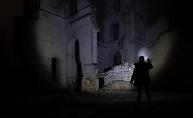 Fototapeta na wymiar a man with a flashlight near the ruins of an old castle