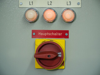 Main switch in red and yellow turned on or off on an electricity switch board with three control or...
