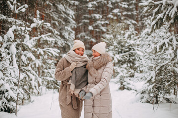 Two young smiling young girls best friends walking in the snowy winter forest