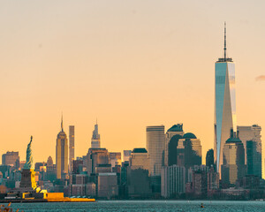New York, NY - USA - Dec 26, 2021: Horizontal sunrise view of the Statue of Liberty in the New York Harbor, with the skyline of Manhattan, World Trade Center and Empire State building behind her.