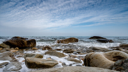 Fototapeta na wymiar italy, december 2021: beach with pebbles, cliff, sea and cloudy sky