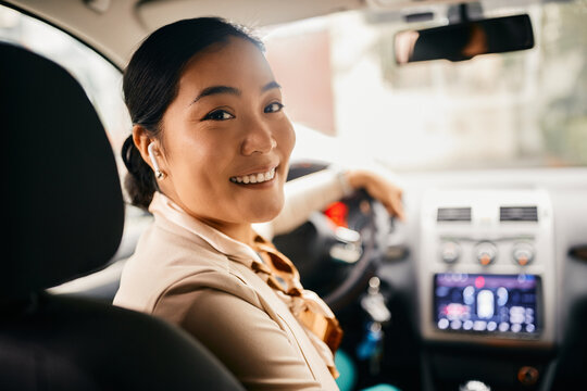 Happy Asian Businesswoman Drives Car In Reverse And Looks At Camera.