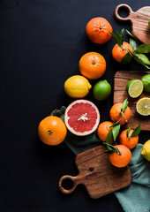 Frische Orangen auf schwarzem Hintergrund, Auswahl Orange, Mandarine, Zitrone, Limette,...